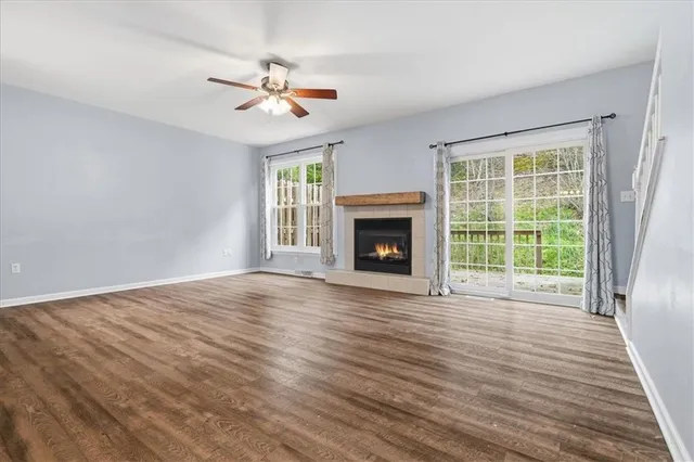 a view of an empty room with wooden floor fireplace and a window