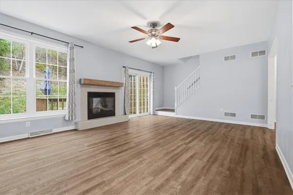 a view of an empty room with wooden floor fireplace and a window