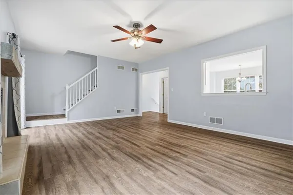 a view of an empty room with wooden floor and a ceiling fan