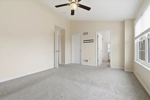 an empty room with windows and ceiling fan