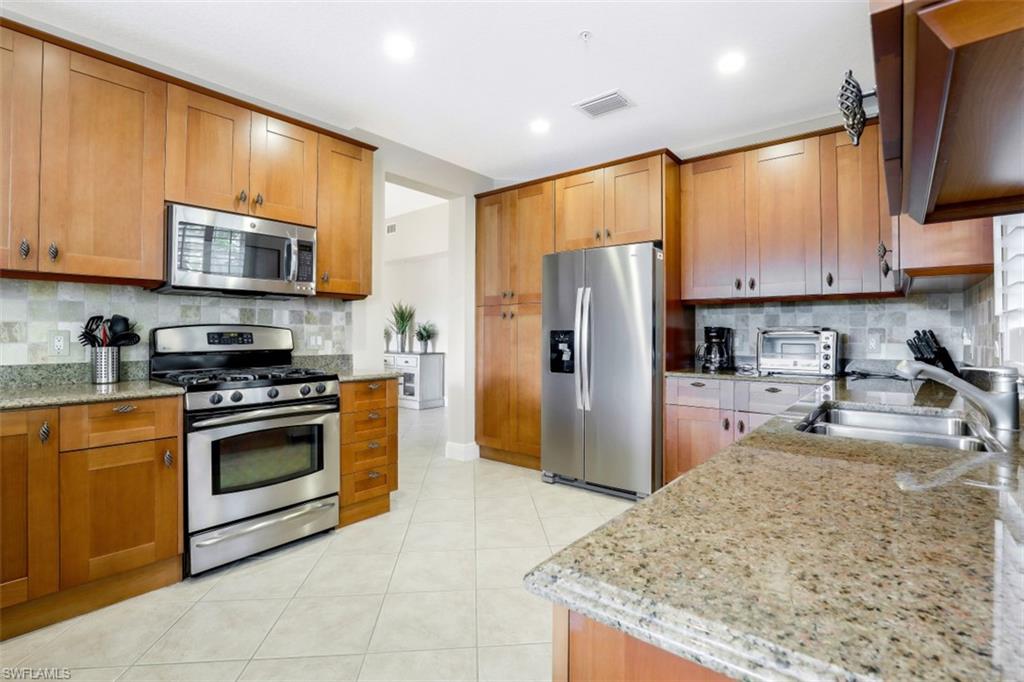 9224 Campanile Circle, Unit 101 Naples, FL 34114 - Photo 13 of 32 a kitchen with stainless steel appliances granite countertop a stove a refrigerator and a sink