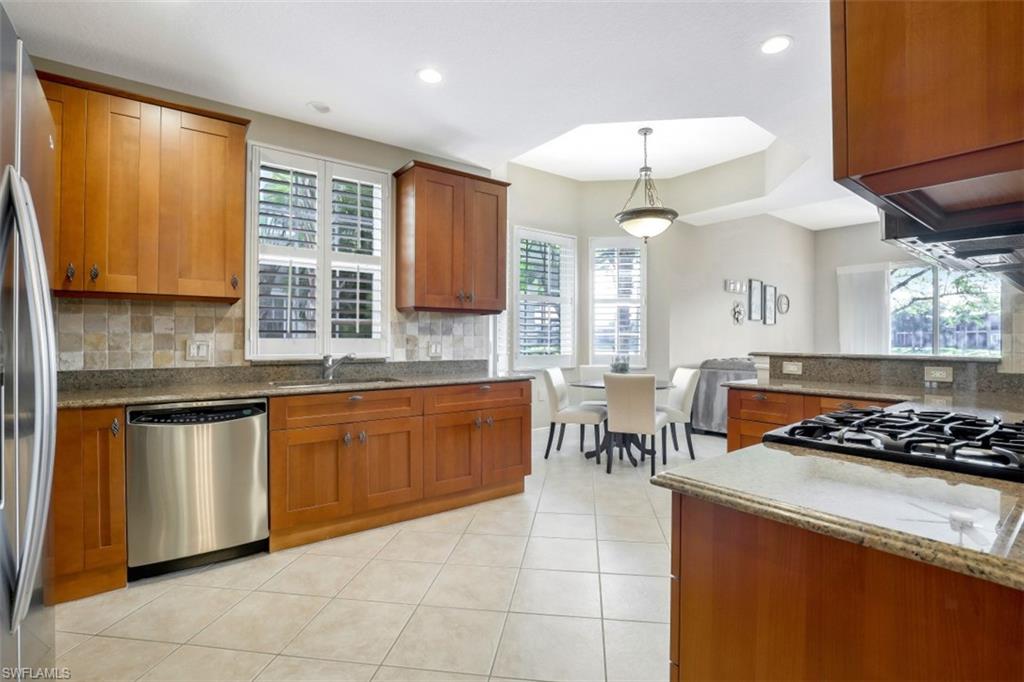 9224 Campanile Circle, Unit 101 Naples, FL 34114 - Photo 14 of 32 a kitchen with stainless steel appliances granite countertop a stove a sink dishwasher and a microwave oven with cabinets