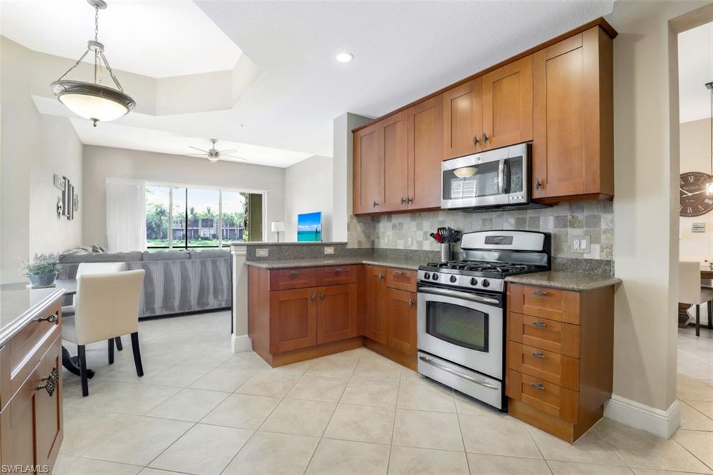 9224 Campanile Circle, Unit 101 Naples, FL 34114 - Photo 15 of 32 a kitchen with stainless steel appliances granite countertop a stove top oven a sink dishwasher a dining table and chairs with wooden floor