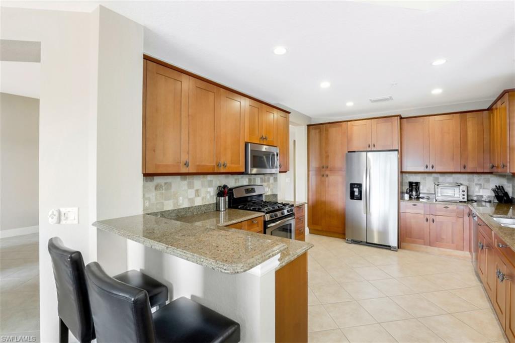 9224 Campanile Circle, Unit 101 Naples, FL 34114 - Photo 16 of 32 a kitchen with stainless steel appliances granite countertop a stove refrigerator sink and cabinets