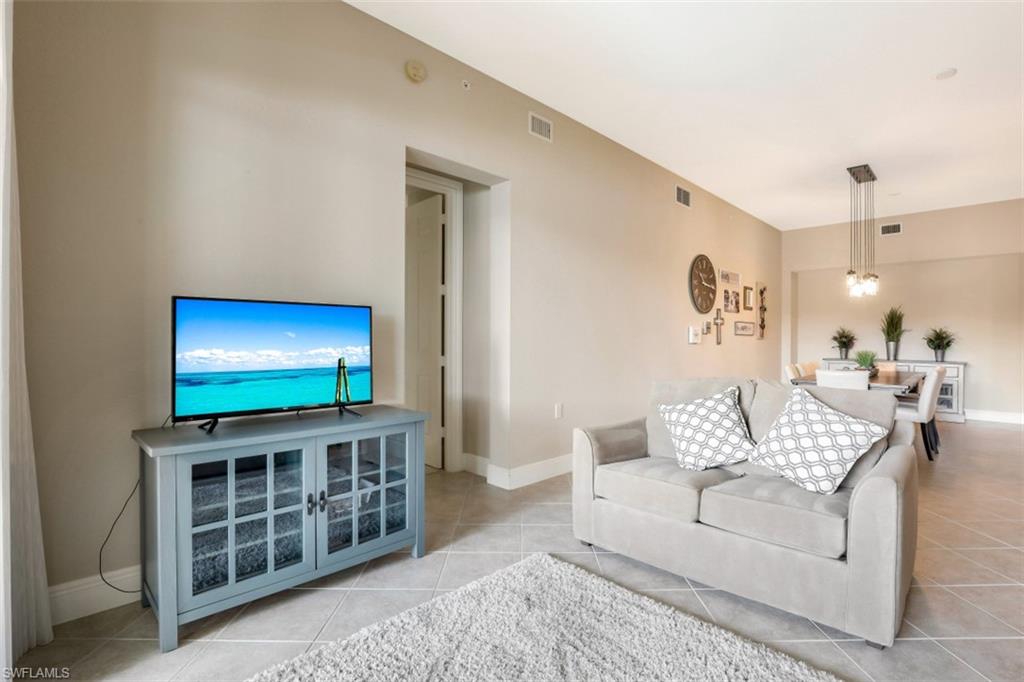 9224 Campanile Circle, Unit 101 Naples, FL 34114 - Photo 7 of 32 a living room with furniture a flat screen tv and a wall painting