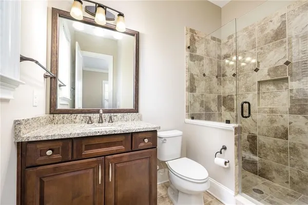 a bathroom with a granite countertop toilet a sink and a mirror