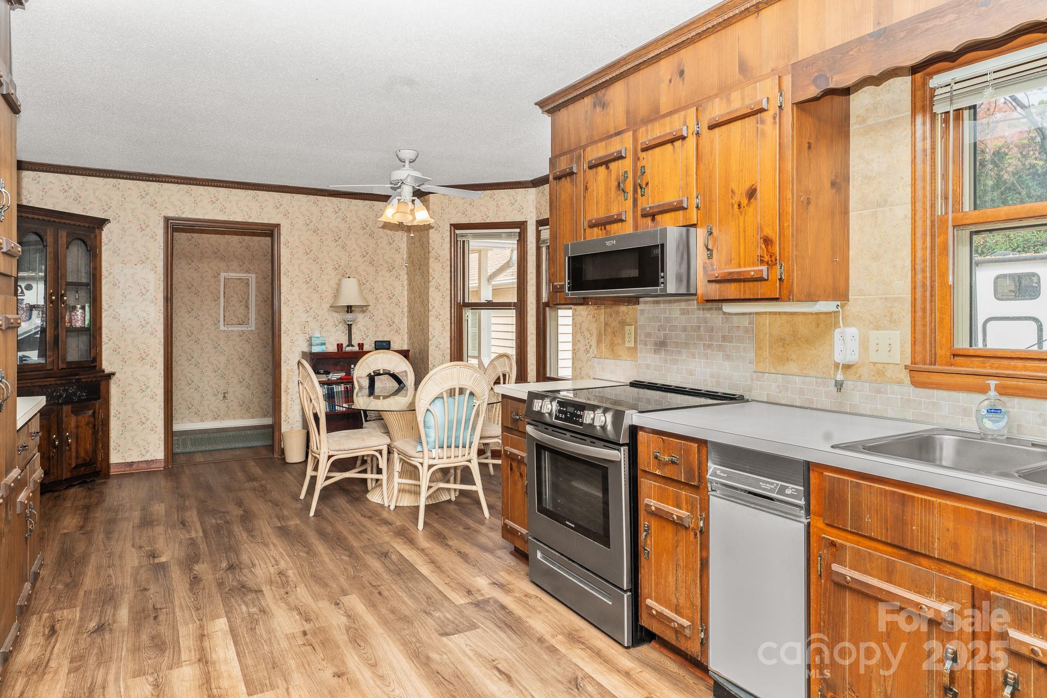 3614 McKee Road Charlotte, NC 28270 - Photo 6 of 29 a kitchen with stainless steel appliances granite countertop a stove top oven a sink a dining table and chairs with wooden floor