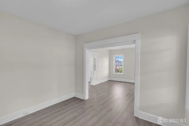 a view of an empty room and wooden floor and a window