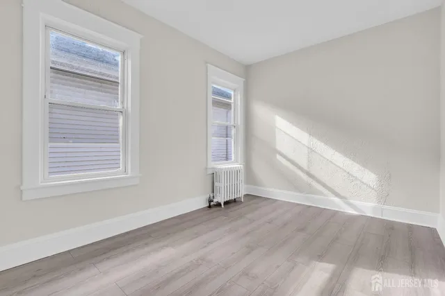 an empty room with wooden floor a ceiling fan and windows