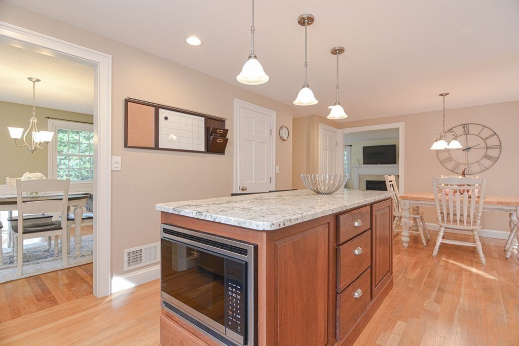 520 Burroughs Road Boxborough, MA 01719 - Photo 6 of 34 a kitchen with granite countertop a stove a sink a dining table and chairs with wooden floor