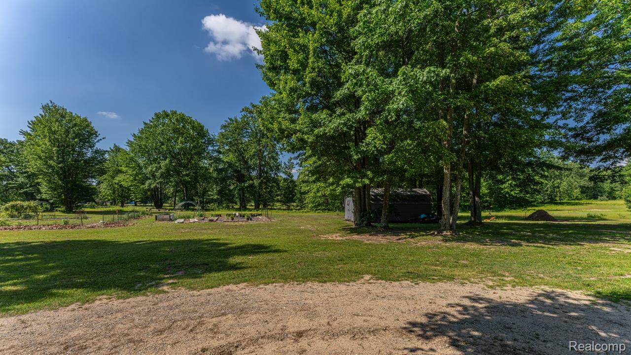 2418 South 41st Road South Cadillac, MI 49601 - Photo 52 of 57 Expansive property featuring mature trees, a small shed, and established garden beds