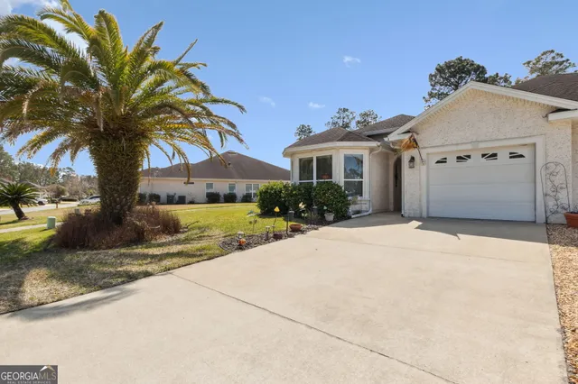 a view of a house with a yard and palm trees