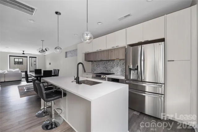 a kitchen with stainless steel appliances a stove a sink a refrigerator and chairs