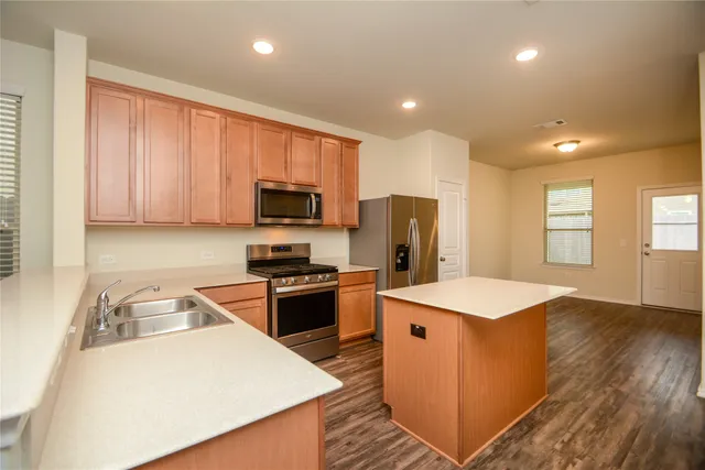 a kitchen that has a lot of cabinets and wooden floor