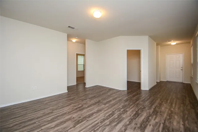 a view of an empty room with wooden floor and a window
