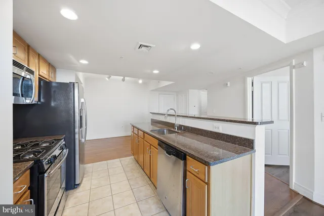 a kitchen with stainless steel appliances granite countertop a refrigerator a stove and a sink