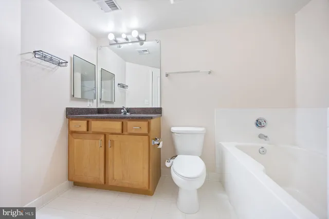 a bathroom with a granite countertop sink a toilet mirror and bathtub