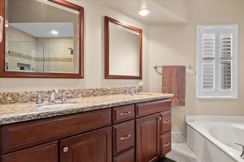 a bathroom with a granite countertop sink mirror and a bathtub