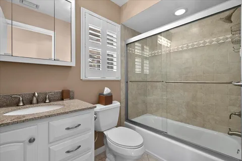 a bathroom with a granite countertop sink a toilet and shower