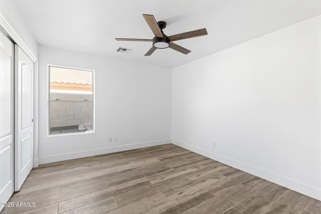 an empty room with wooden floor and windows