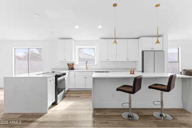 a kitchen with white cabinets appliances and chairs