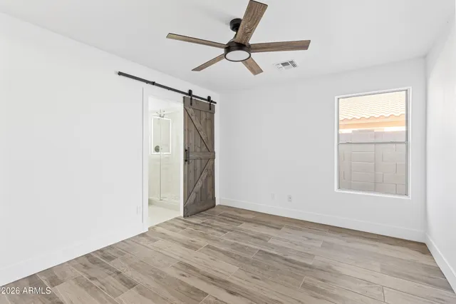 an empty room with wooden floor closet and windows