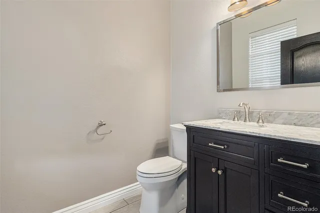 a bathroom with a granite countertop toilet sink a mirror and vanity