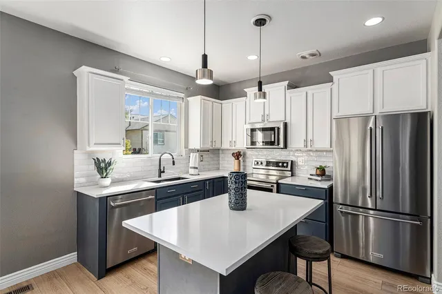 a kitchen with stainless steel appliances granite countertop a sink a stove a refrigerator and island