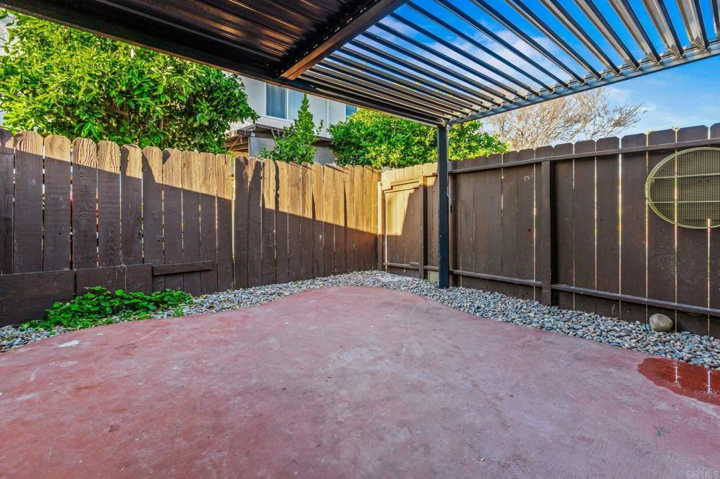 3446 Los Mochis Way Oceanside, CA 92056 - Photo 16 of 17 a backyard of a house with a table and chairs under an umbrella