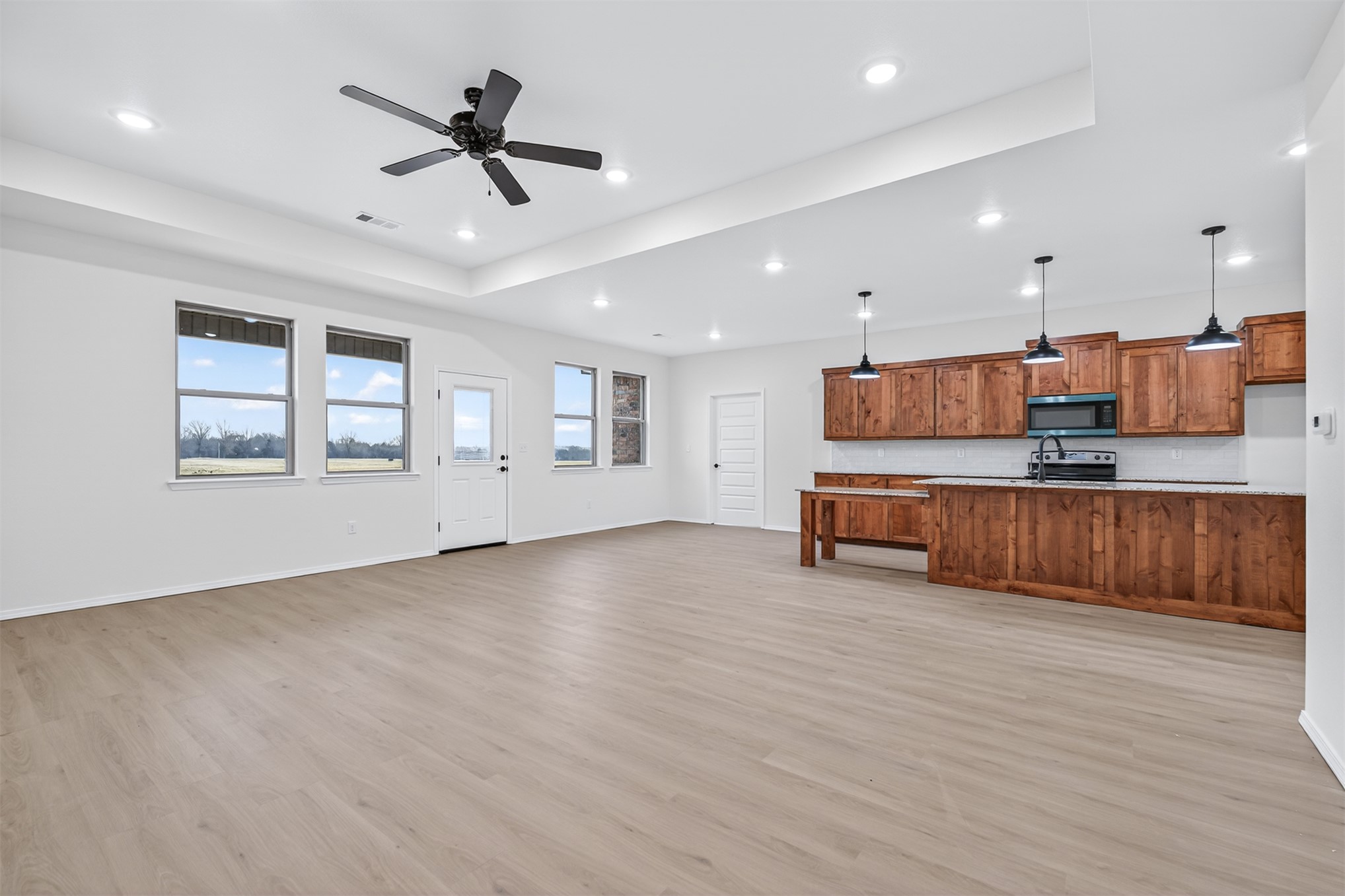 124 Countryside Way Pocola, OK 74902 - Photo 23 of 39 Spacious living area featuring wood-finish flooring, a tray ceiling with recessed lighting and a ceiling fan, and multiple large windows