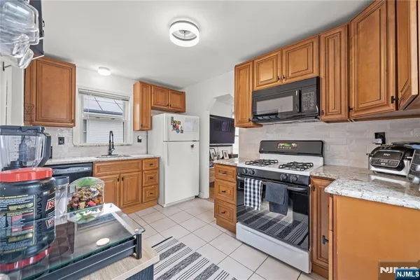 a kitchen with stainless steel appliances granite countertop a stove a sink dishwasher and a refrigerator with wooden cabinets