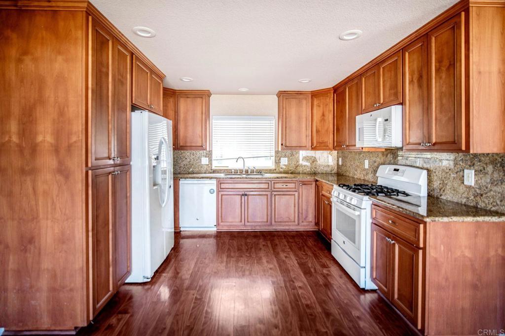 4990 Del Road Loomis, CA 95650 - Photo 6 of 22 a kitchen with stainless steel appliances granite countertop a refrigerator a sink dishwasher a stove and white countertops with wooden floor