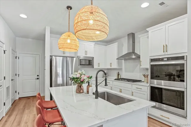 a kitchen with stainless steel appliances granite countertop a sink a stove and a wooden floors