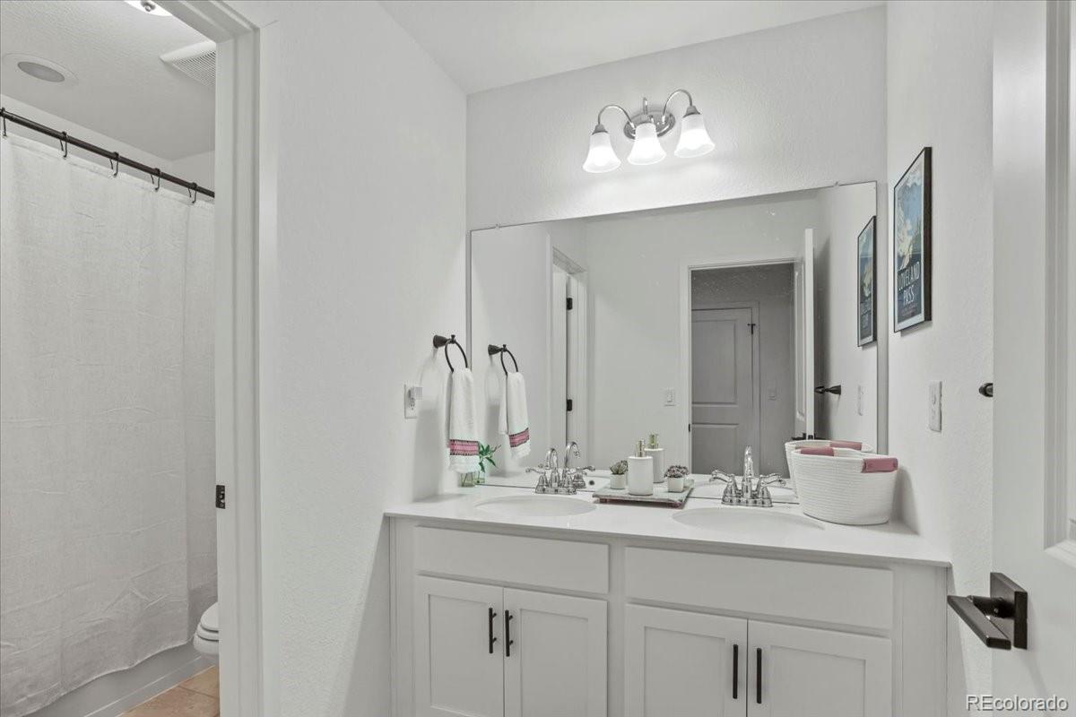 9790 Mount Kataka Point Littleton, CO 80125 - Photo 21 of 32 a bathroom with a double vanity sink and a mirror