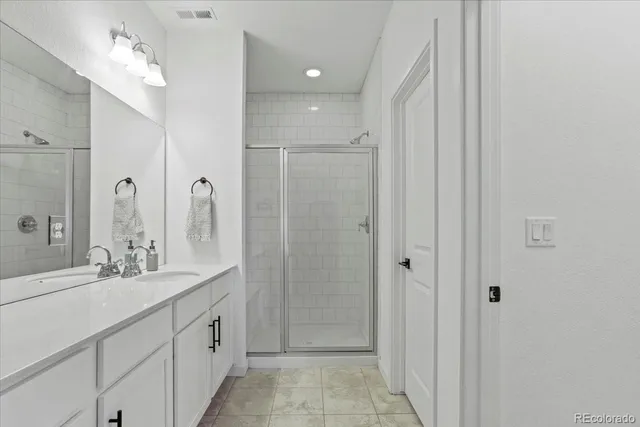 a bathroom with a double vanity sink mirror and shower