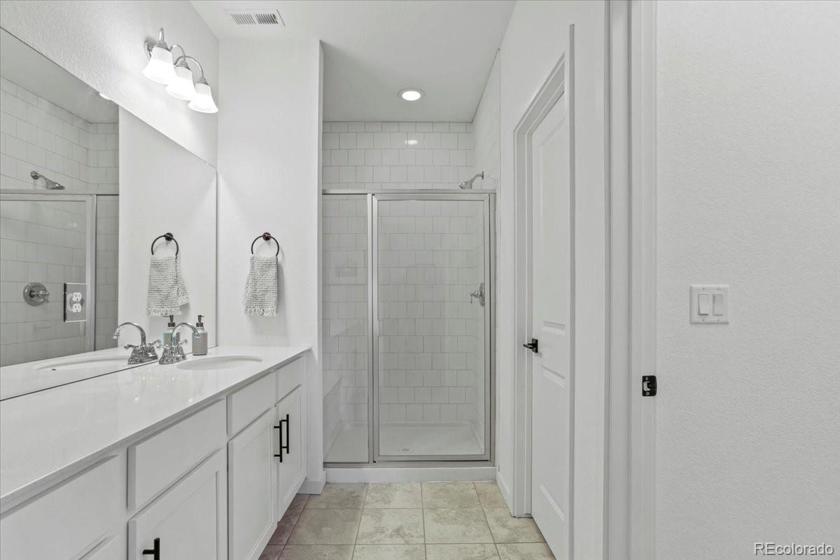 9790 Mount Kataka Point Littleton, CO 80125 - Photo 26 of 32 a bathroom with a double vanity sink mirror and shower