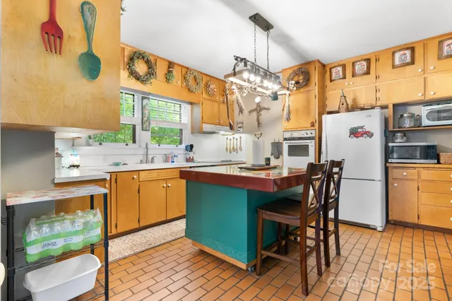 a kitchen with stainless steel appliances granite countertop a sink dishwasher a microwave oven a dining table and chairs with wooden floor