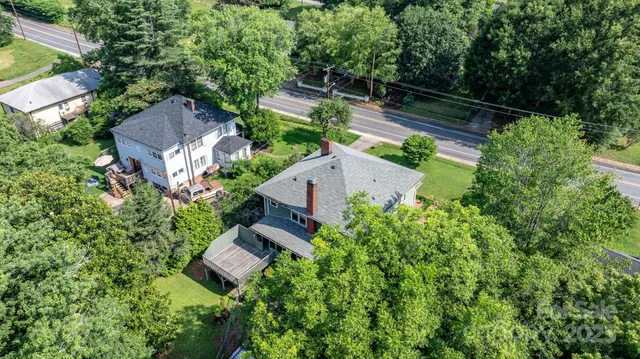 an aerial view of residential houses with outdoor space and trees all around