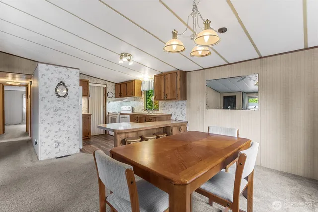 a dining room with stainless steel appliances kitchen island granite countertop a table chairs and a refrigerator
