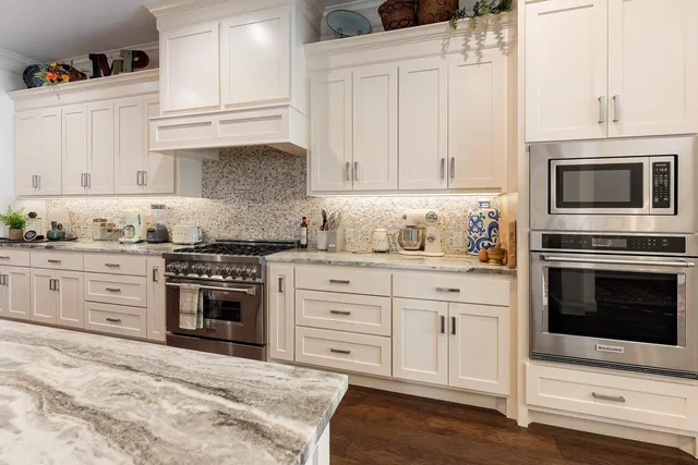 a kitchen with granite countertop white cabinets and stainless steel appliances