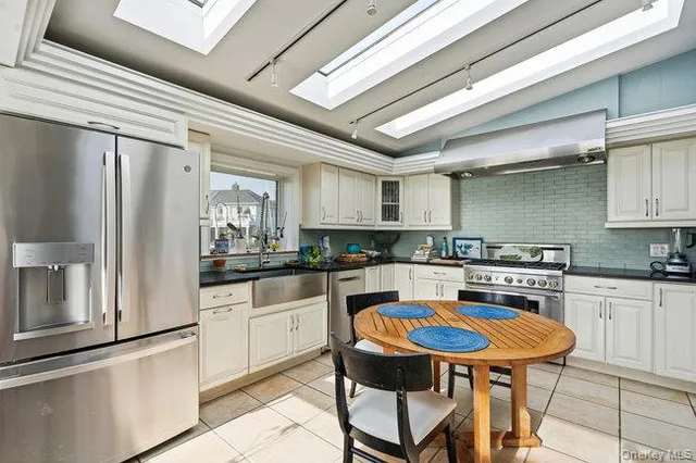 a kitchen with stainless steel appliances a stove a sink dishwasher and white cabinets with wooden floor