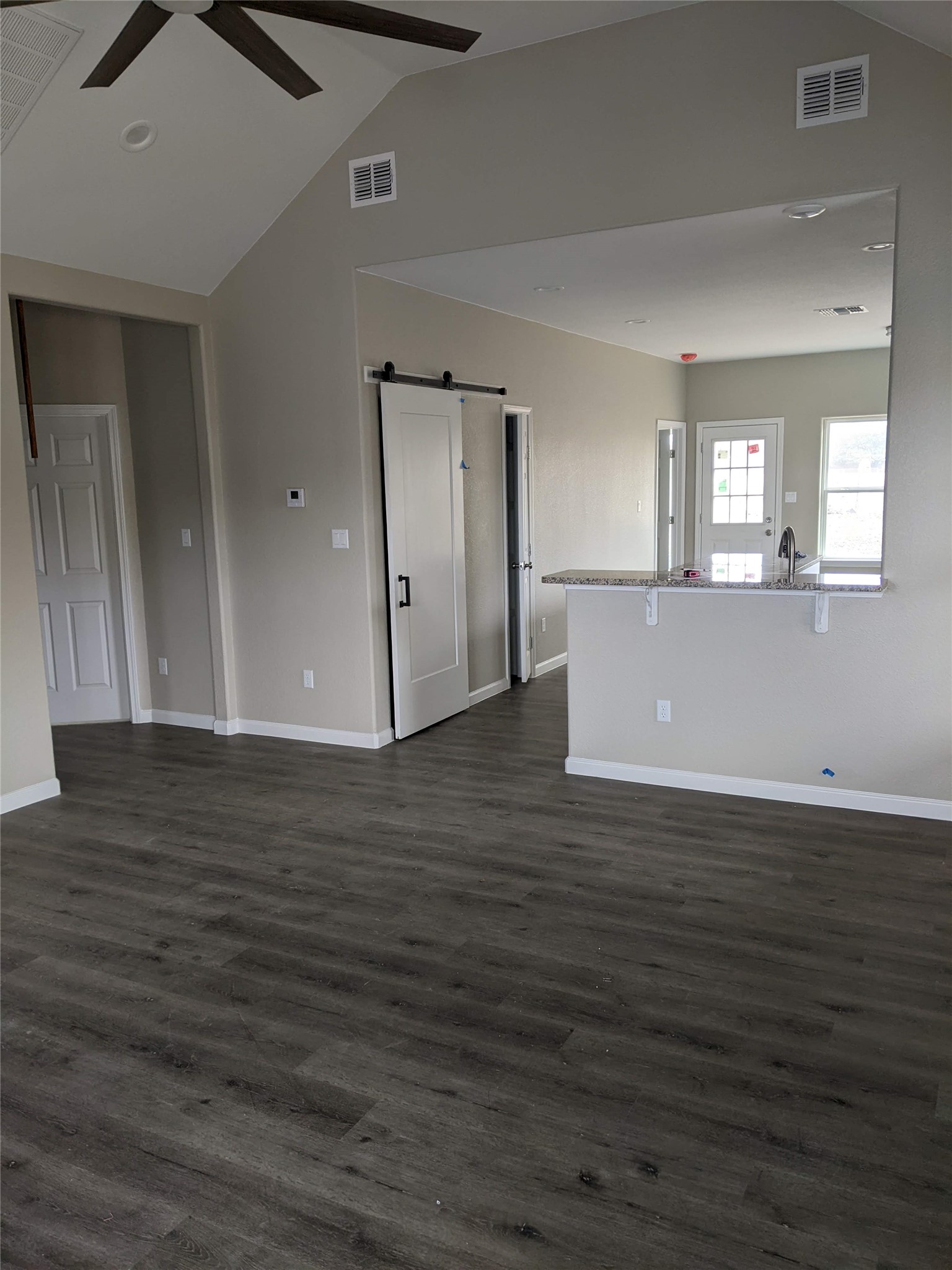 906 Kate Street, Unit A Lockhart, TX 78644 - Photo 3 of 15 Unfurnished living room featuring a barn door, a ceiling fan, and dark wood vinyl finished floors