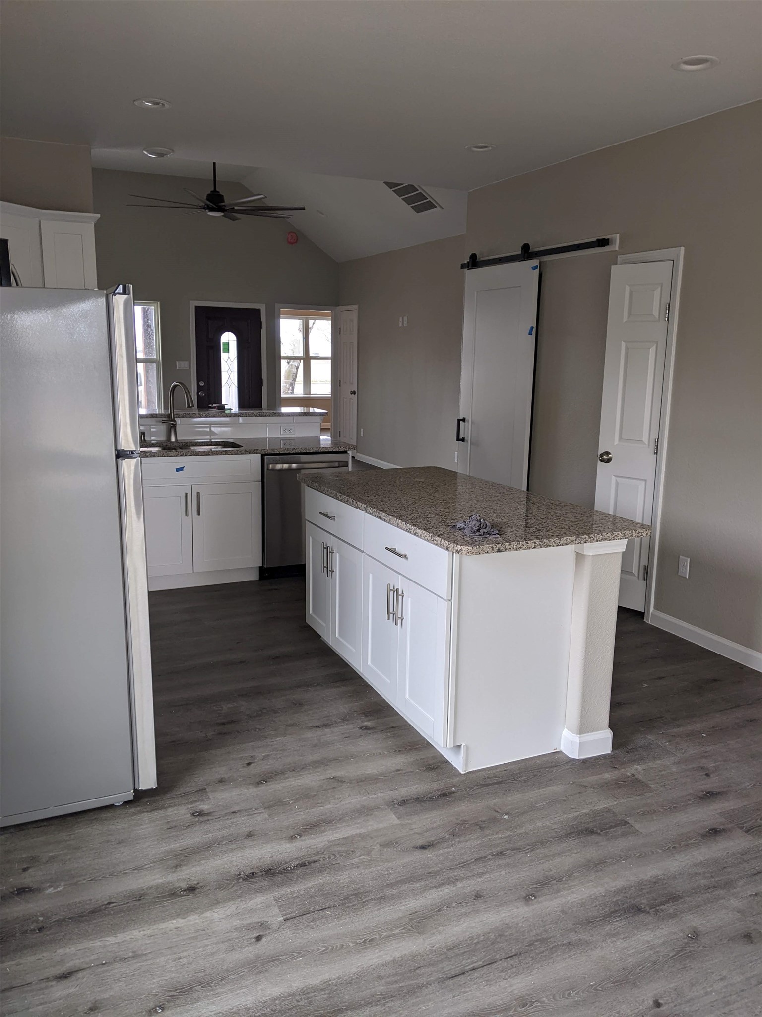 906 Kate Street, Unit A Lockhart, TX 78644 - Photo 4 of 15 Kitchen with a barn door, stainless steel appliances, white cabinetry, a center island, and lofted ceiling
