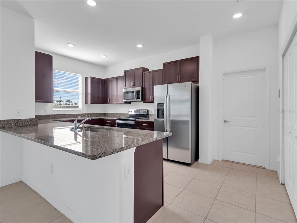 12408 Crystal Jade Way Parrish, FL 34219 - Photo 17 of 51 a kitchen with stainless steel appliances granite countertop a refrigerator a stove a sink and a microwave