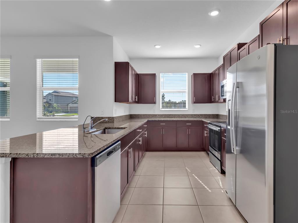 12408 Crystal Jade Way Parrish, FL 34219 - Photo 18 of 51 a kitchen with granite countertop a refrigerator stove top oven and sink
