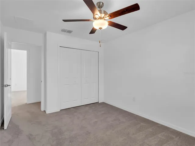 an empty room with a ceiling fan and a window