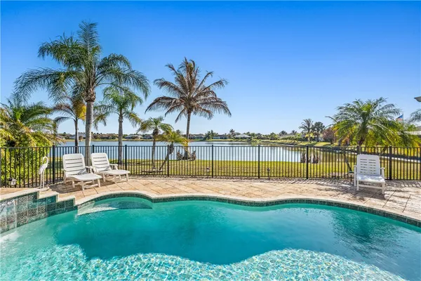 a view of a swimming pool with a lawn chairs and palm tree