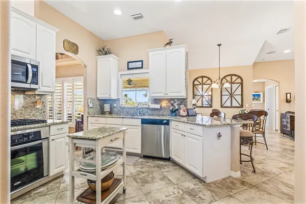 a kitchen with stainless steel appliances a stove a sink dishwasher a microwave oven with white cabinets and wooden floor