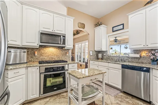 a kitchen with granite countertop a stove top oven microwave and cabinets