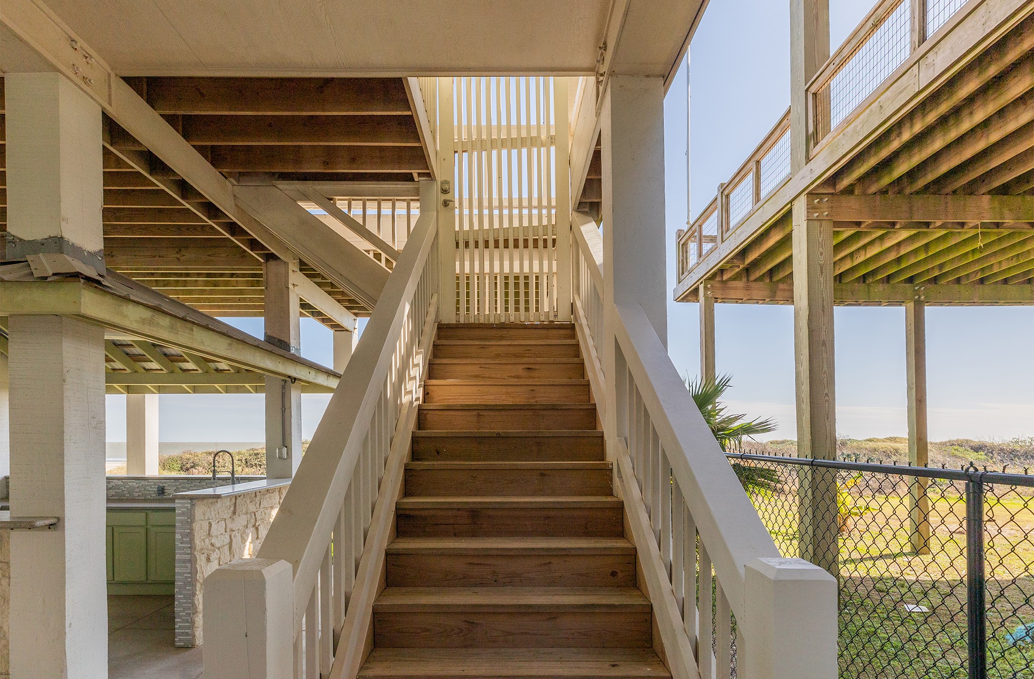 843 South Jacks Road Crystal Beach, TX 77650 - Photo 13 of 45 An elevated wooden staircase leading up to a covered deck area, with views of the outdoors and nearby water.